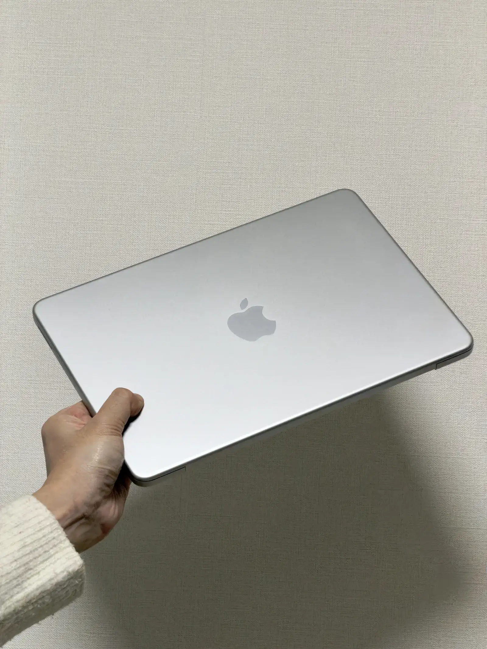 MacBook Neoを片手で持ち上げている様子。軽量で持ち運びやすい